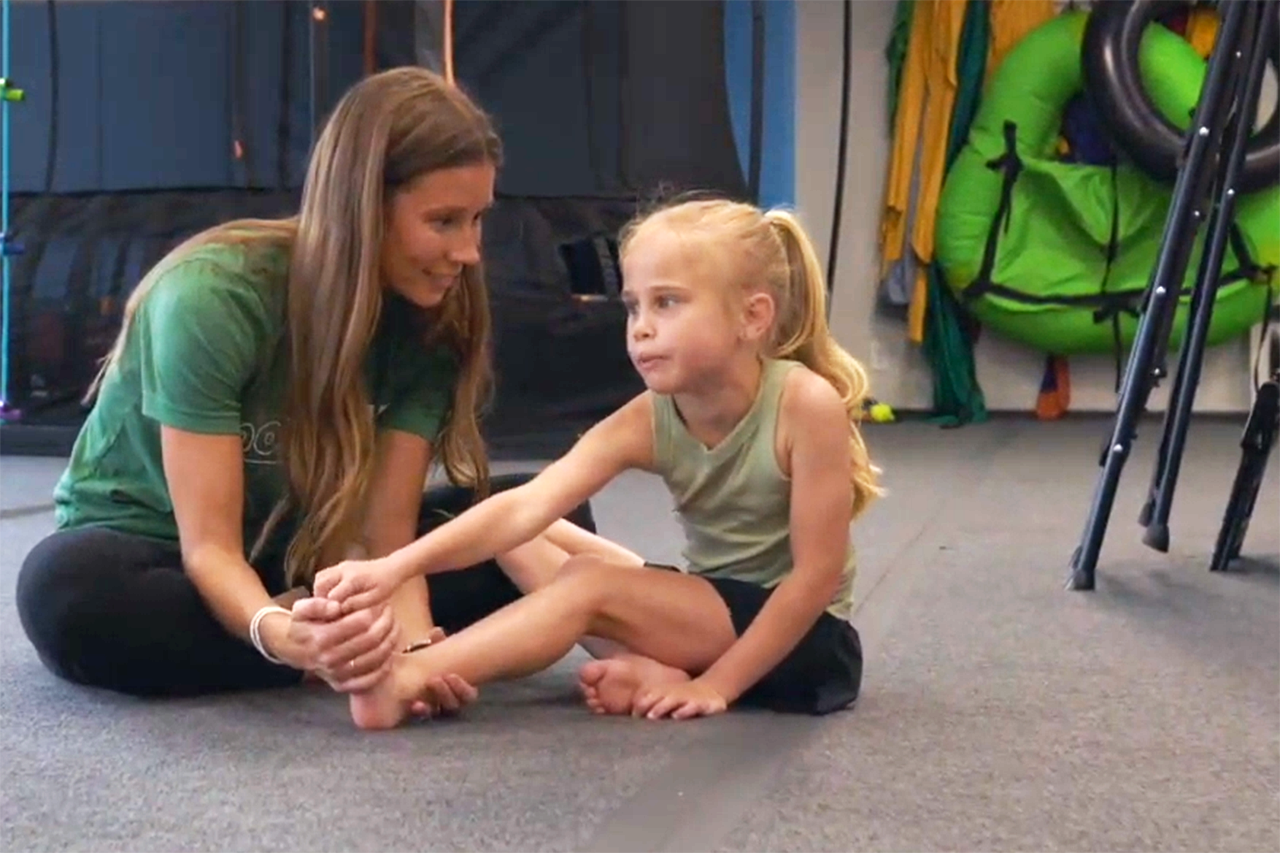 Child engaged in pediatric physical therapy session with therapist, focusing on movement and coordination in supportive environment.