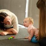 Toddler taking first steps with support from a pediatric physical therapist at Move U in Sioux Falls SD