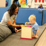 Pediatric speech-language pathologist at Move U engaging a toddler in a communication activity during a speech therapy session in Sioux Falls