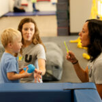Young child resting during physical play, showing signs of fatigue that may benefit from pediatric PT at Move U Sioux Falls